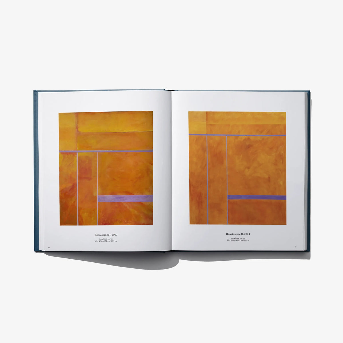 Art book open spread with two warm orange abstract paintings on white pages