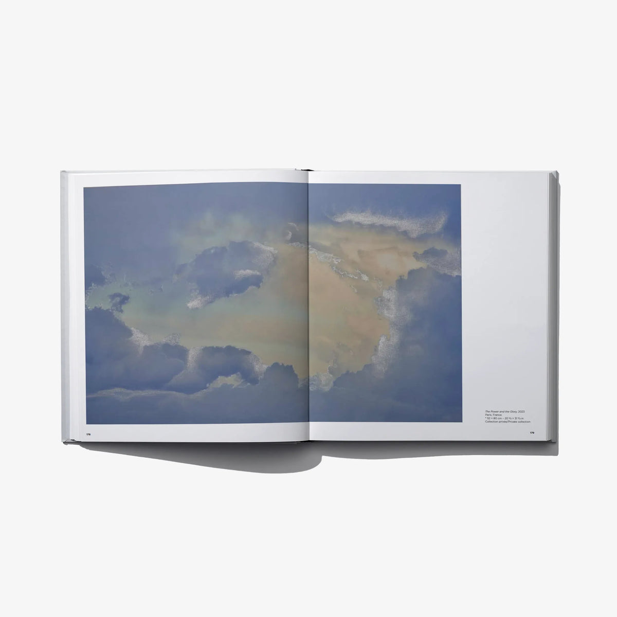 Open photo book with blue sky and cloud print across two panels on the right spread