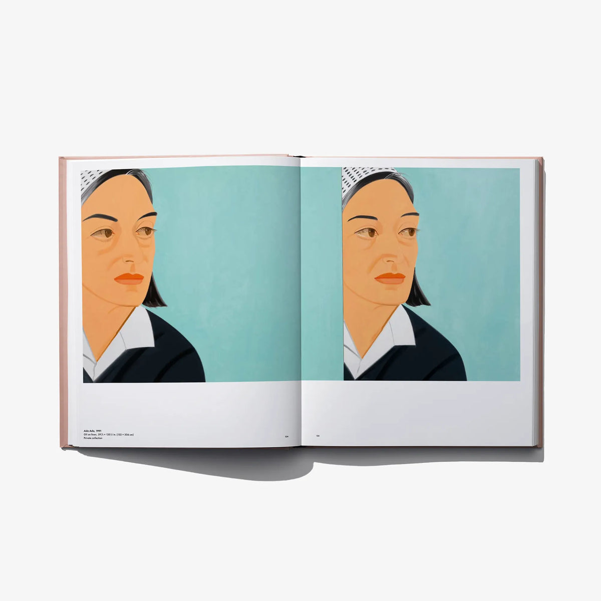 Open art book spread with two close-up portrait faces on a blue background