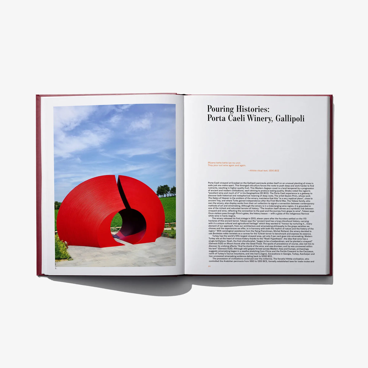 Open book spread with red circular outdoor sculpture photo on left and text on right page.