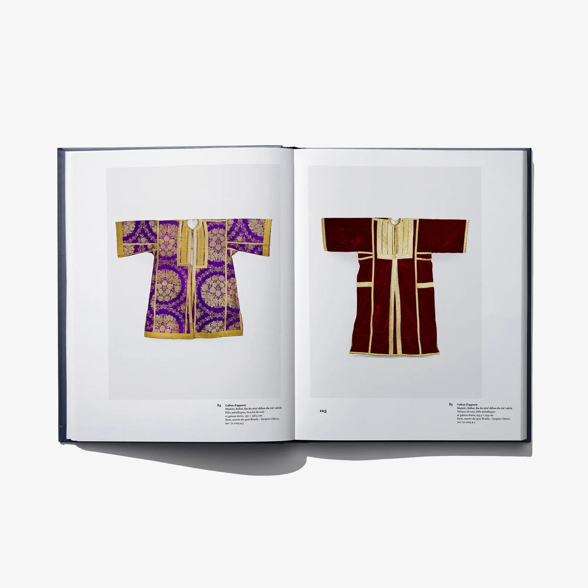 Open Au Fil de L'Or book spread: purple and red embroidered garments with gold trim