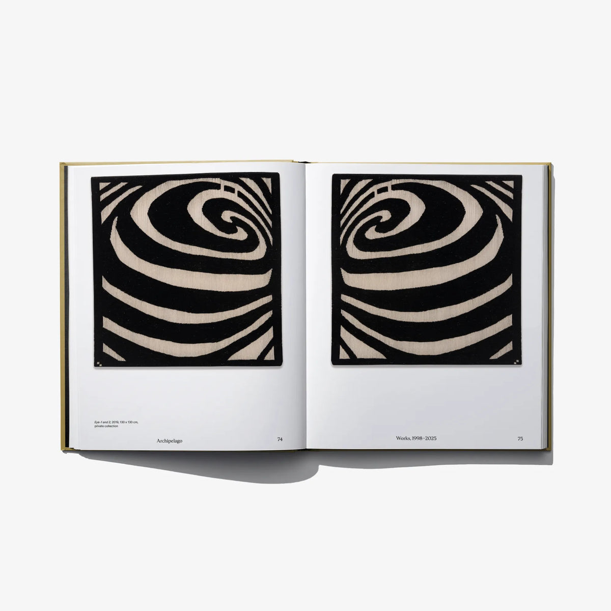 Open art book featuring two black-and-cream spiral swirl abstract prints