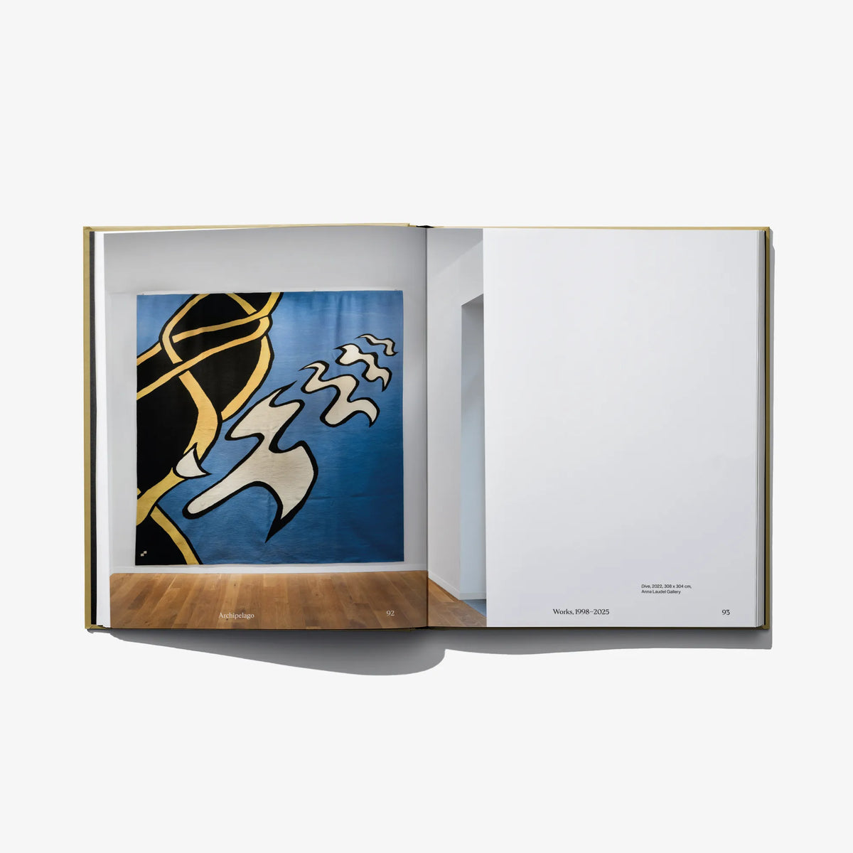 Open art book with framed blue abstract artwork on the left and blank page on the right