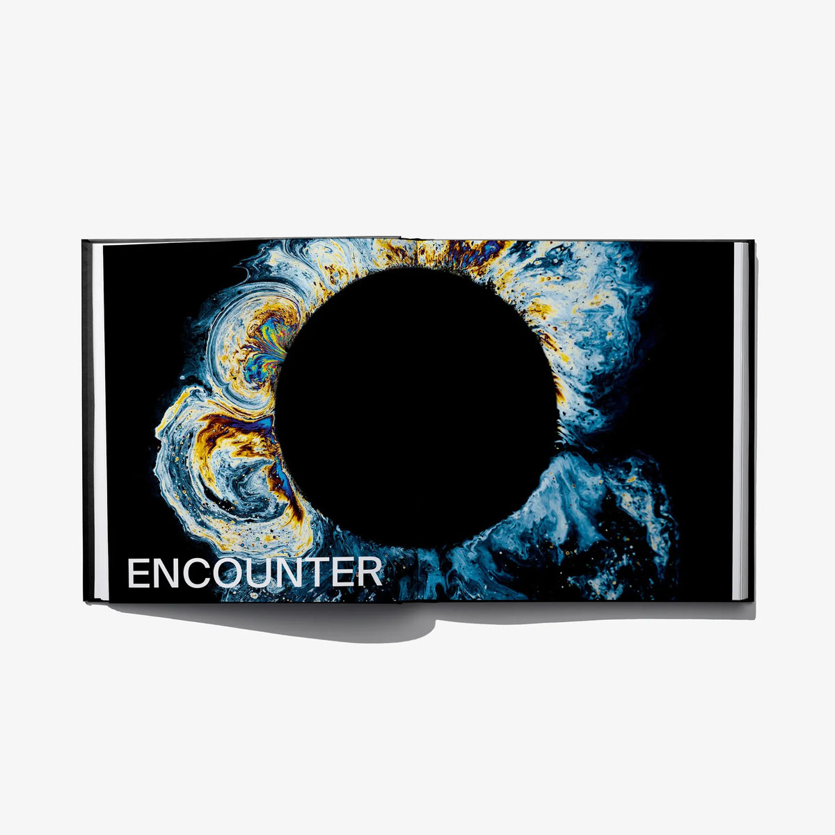 Open hardcover art book with blue swirl artwork and “ENCOUNTER” title