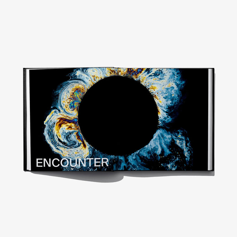Open hardcover art book with blue swirl artwork and “ENCOUNTER” title