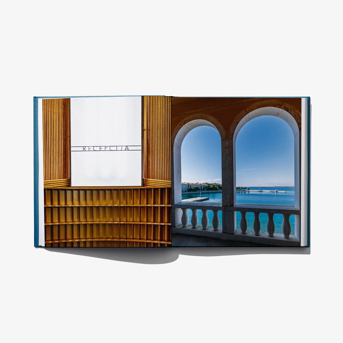 Open photo book spread with warm wood interior and arched window sea view.
