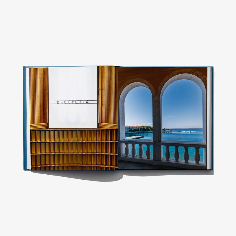 Open photo book spread with warm wood interior and arched window sea view.