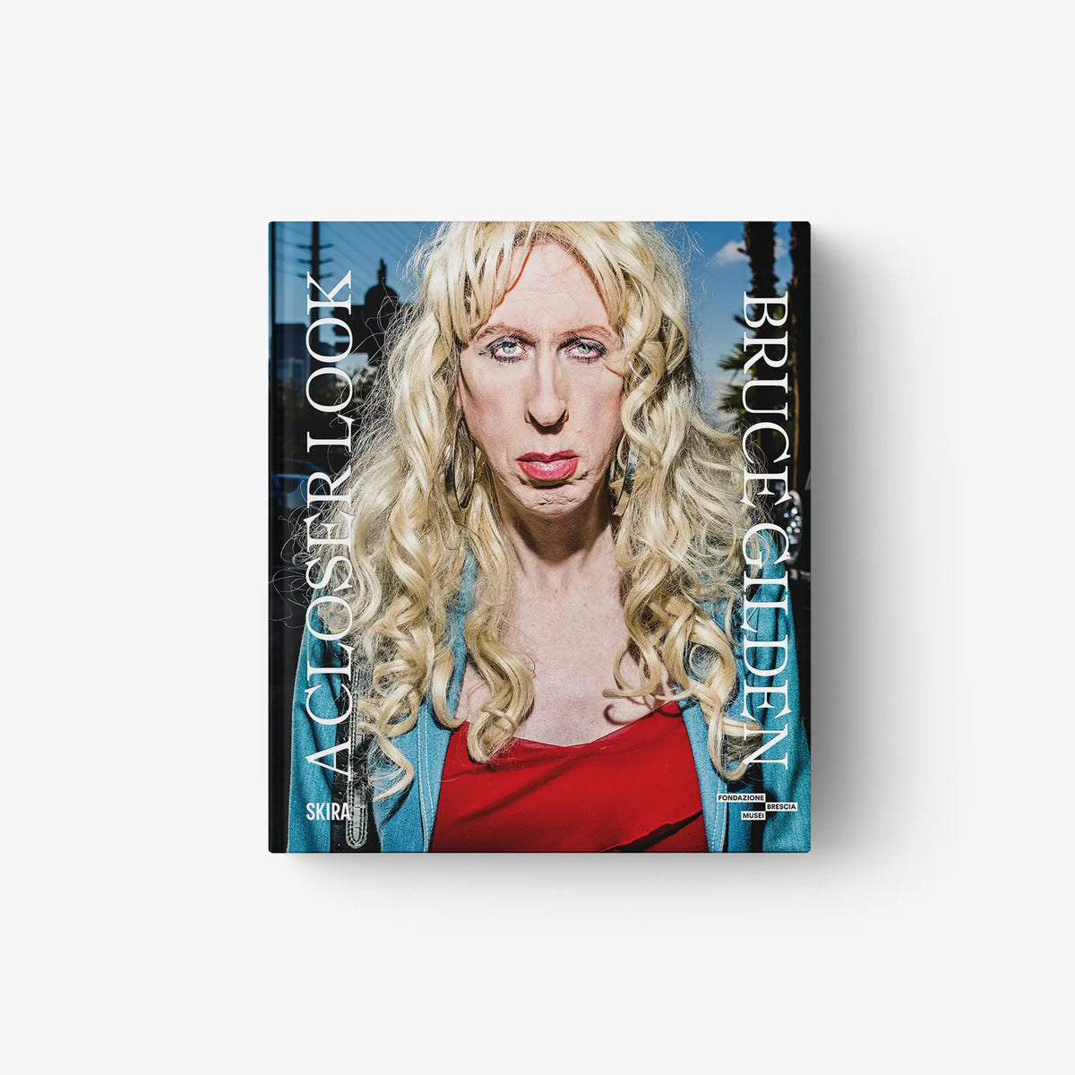 Photo book cover with blonde woman close-up in red top against blue background