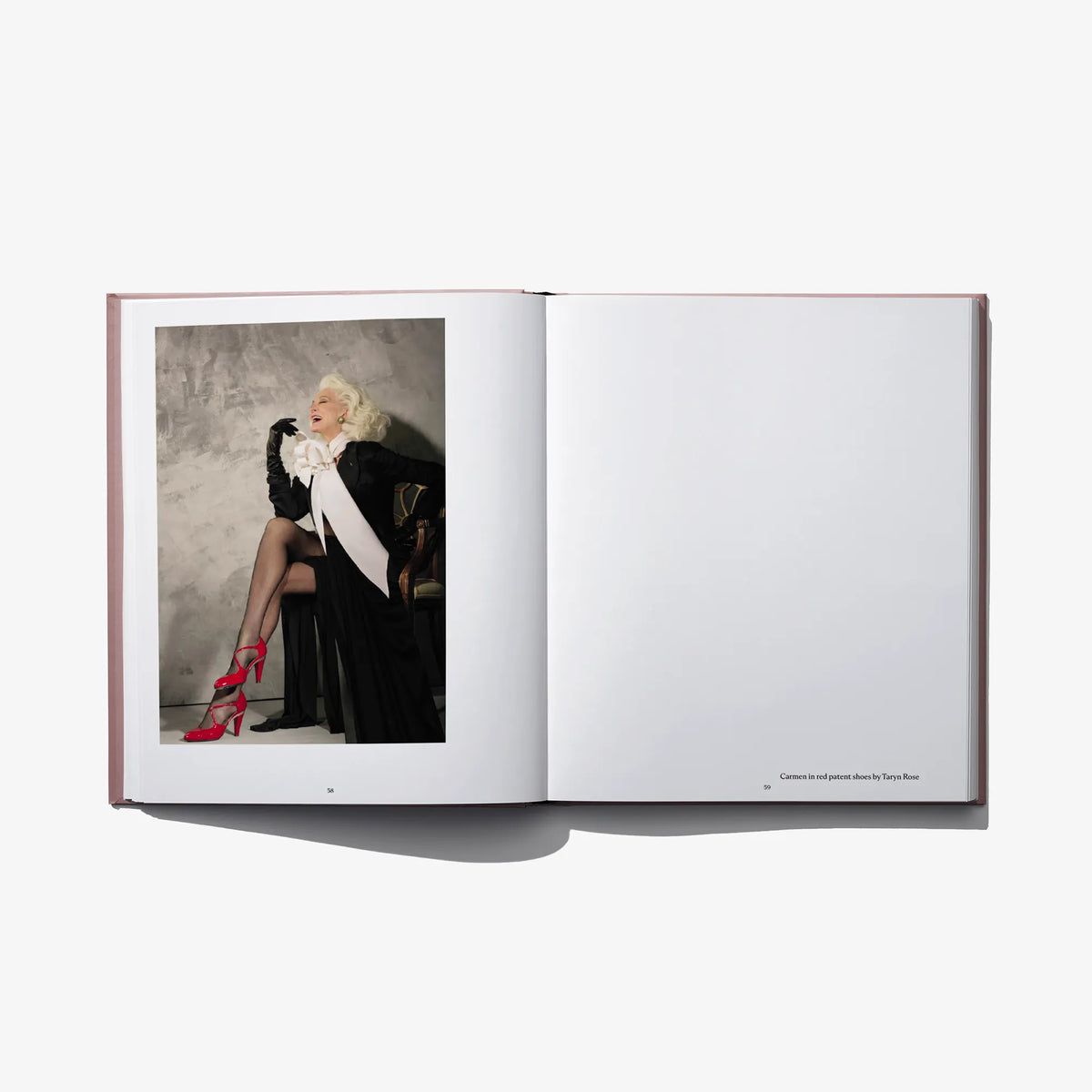 Open hardcover fashion book with color photo of model in black dress and red heels