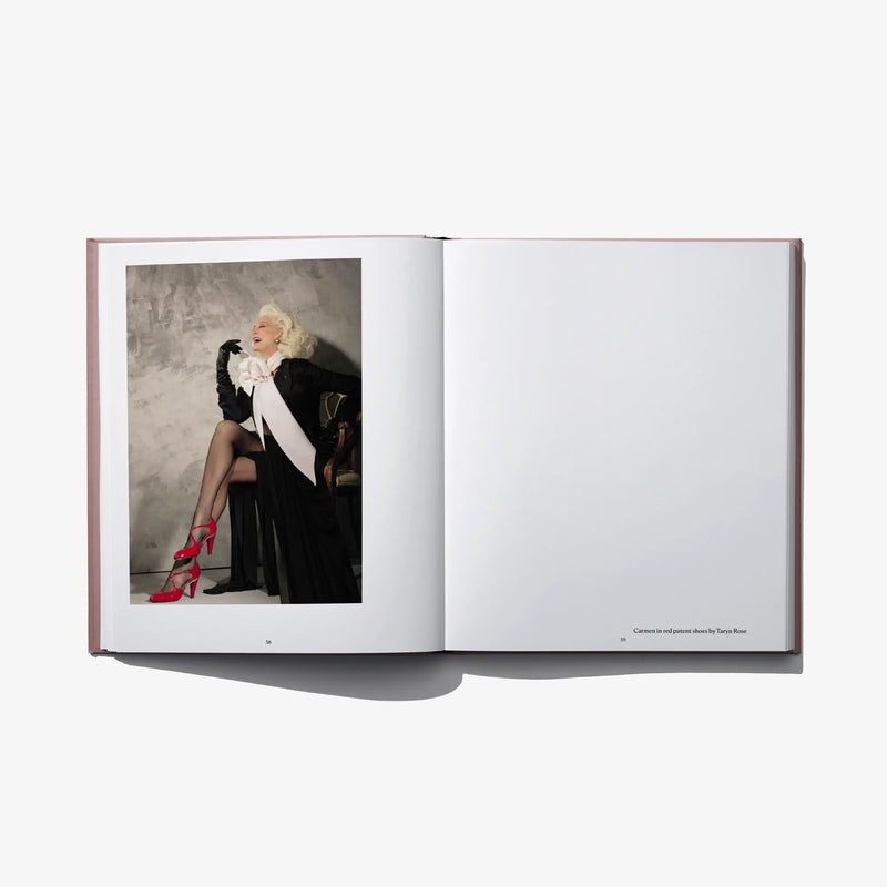 Open hardcover fashion book with color photo of model in black dress and red heels