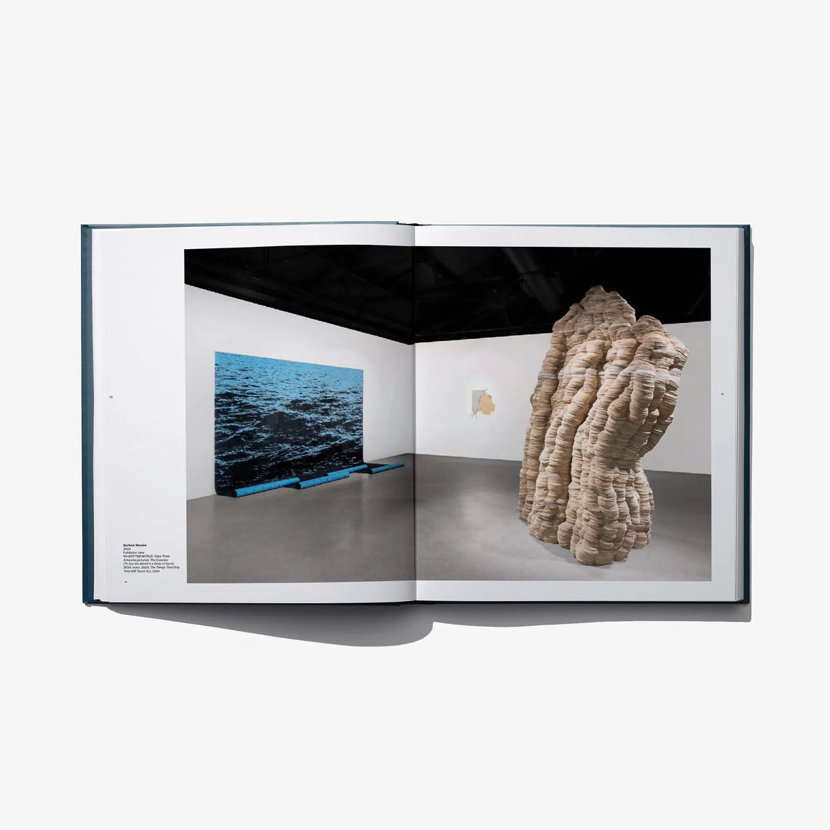 Open art book spread with beige draped sculpture and a small ocean landscape photo.