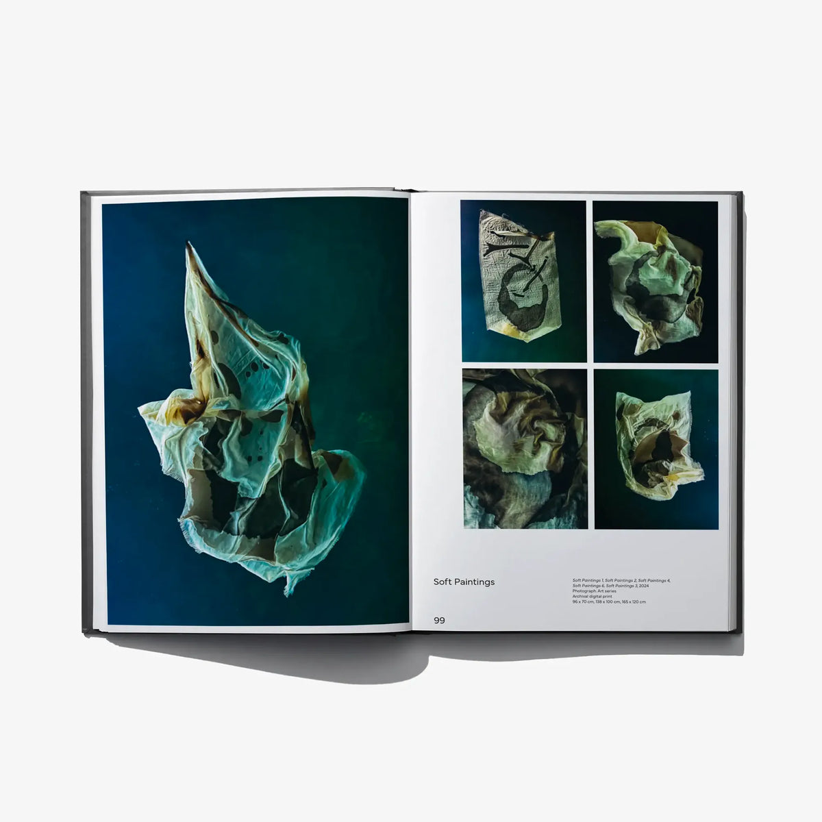 Open art book pages showing teal and gold folded abstract shapes with small photo grid