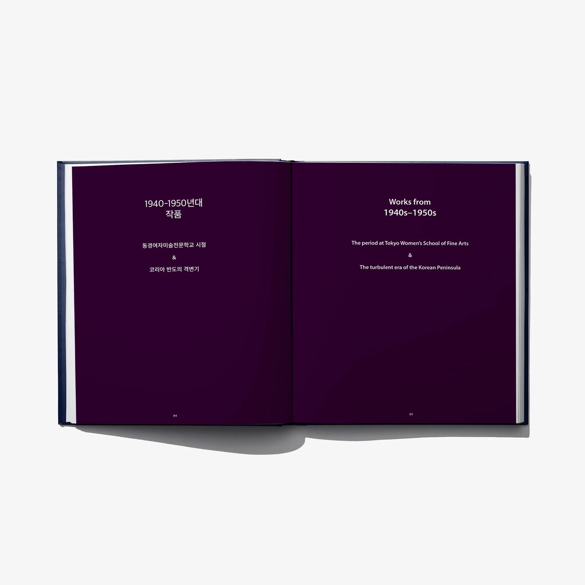 Open art book spread with dark purple pages and white headings
