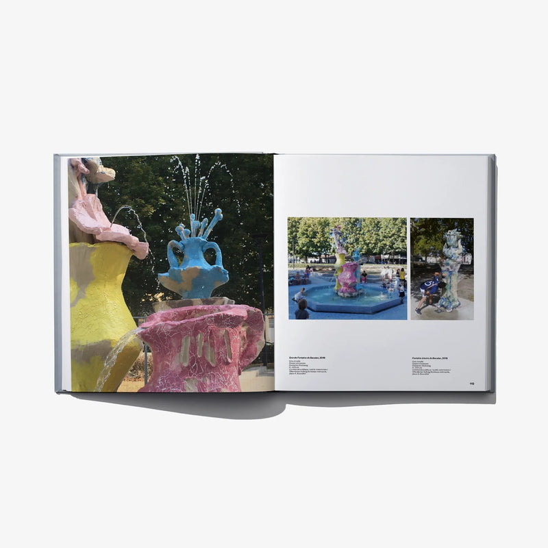 Open hardcover art book spread with colorful sculpture images and a pool scene