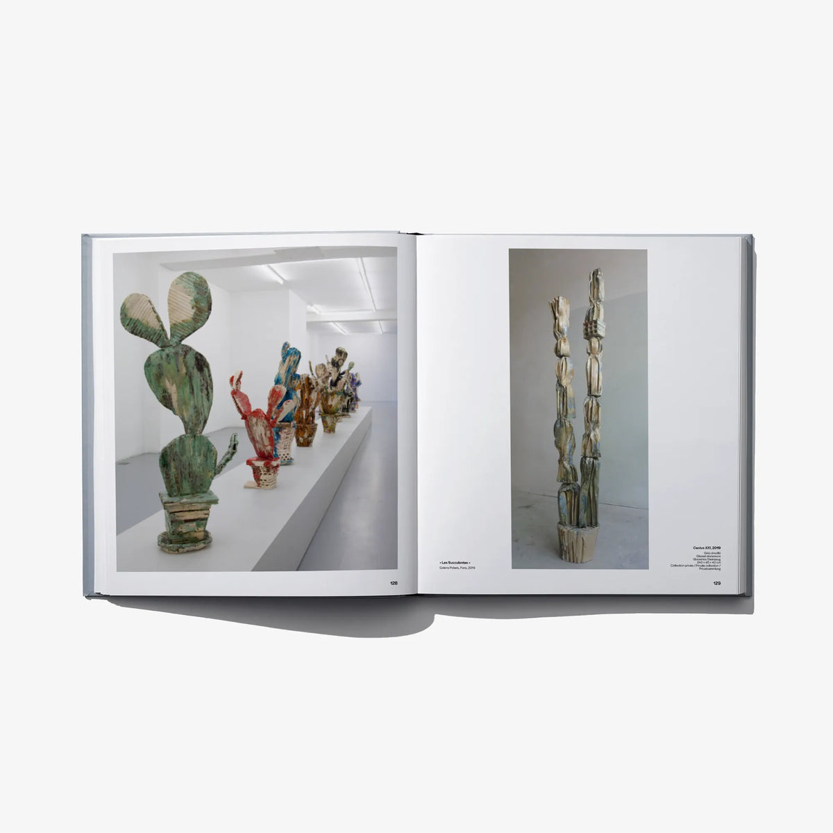 Open hardcover art book featuring green and blue sculptural photos in a gallery