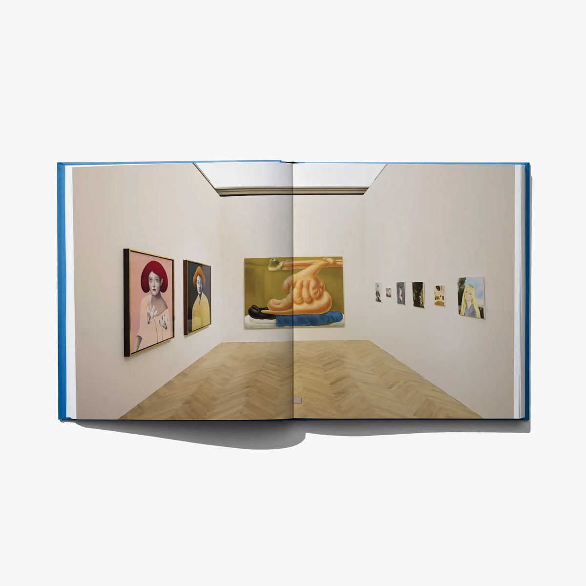 Open art book showing a gallery room with framed portraits and small prints
