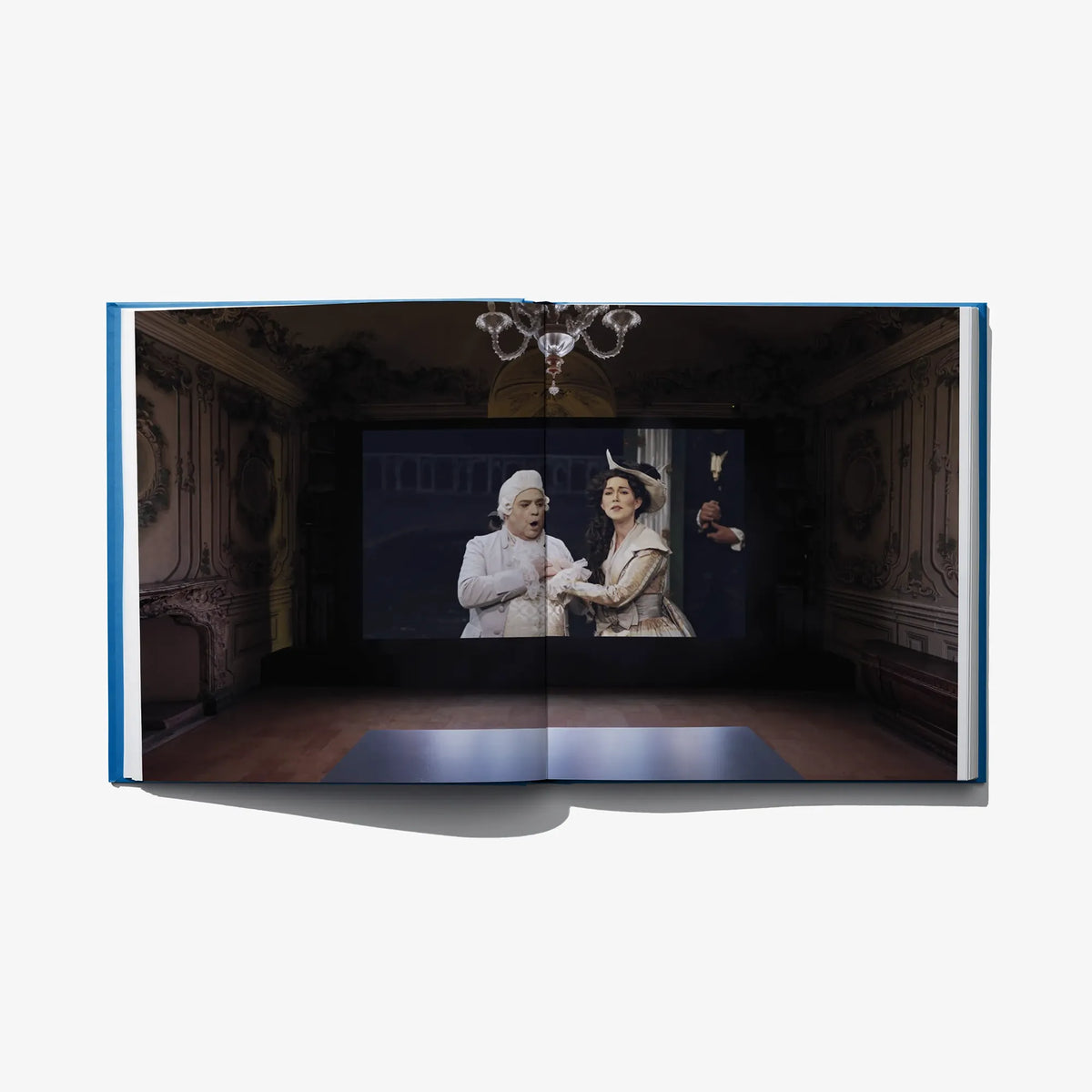 Open art book with photo artwork of performers on an ornate stage