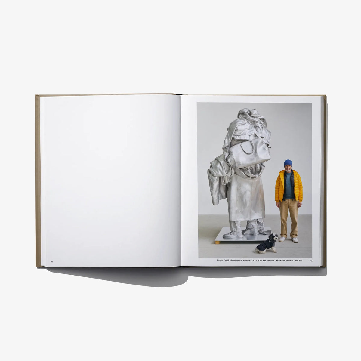 Open art book with black-and-white sculpture and a person standing on right page.