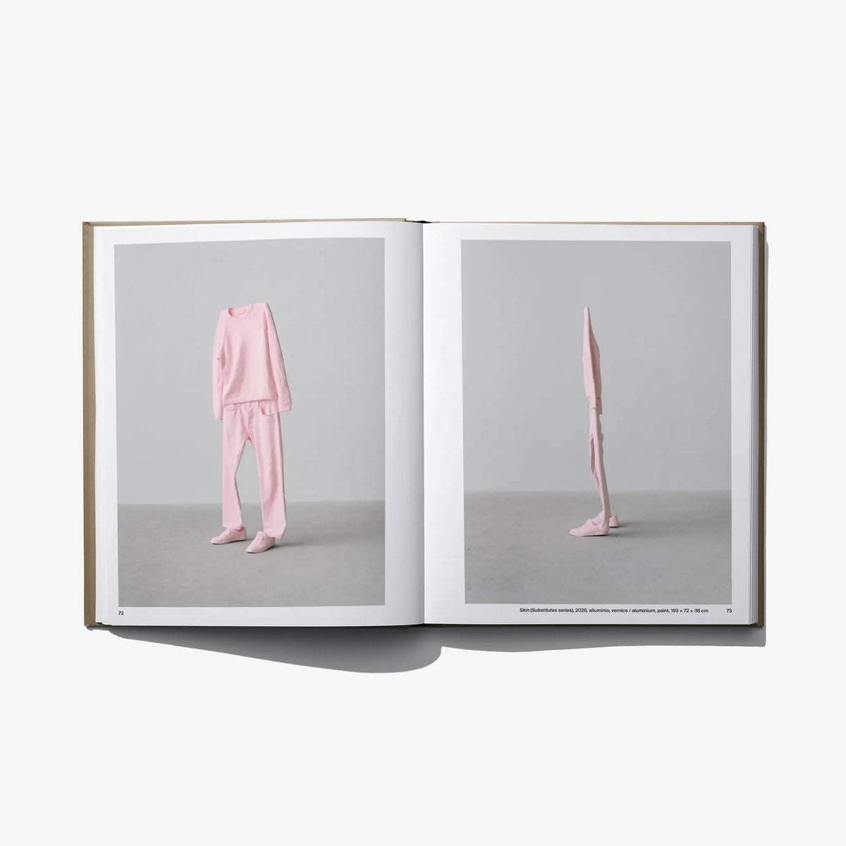 Open art book with a pink-clad figure standing on right page.
