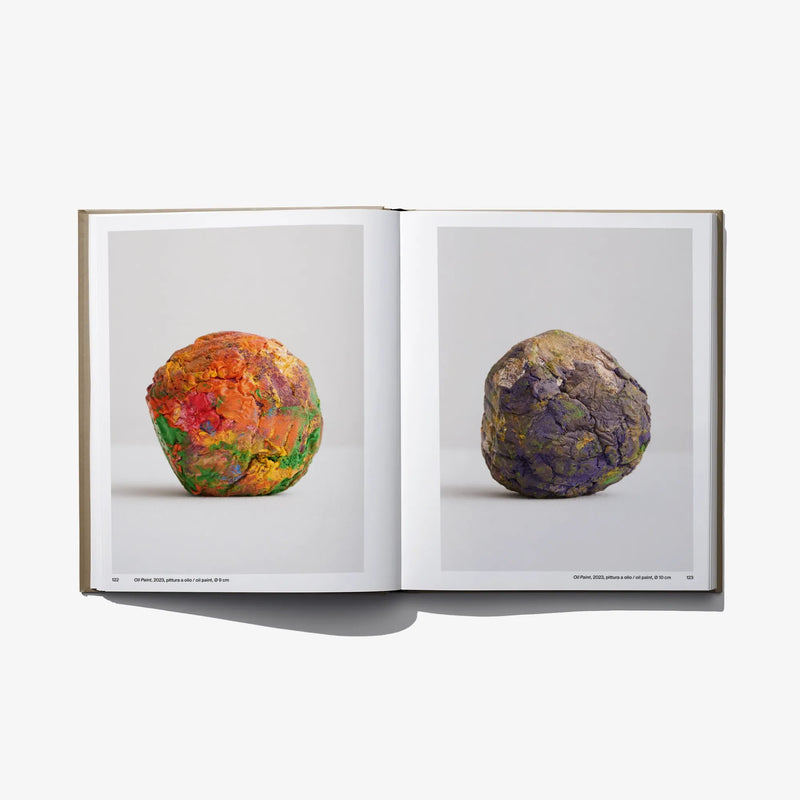 Open art book showing two spherical sculptures: colorful left, dark right.