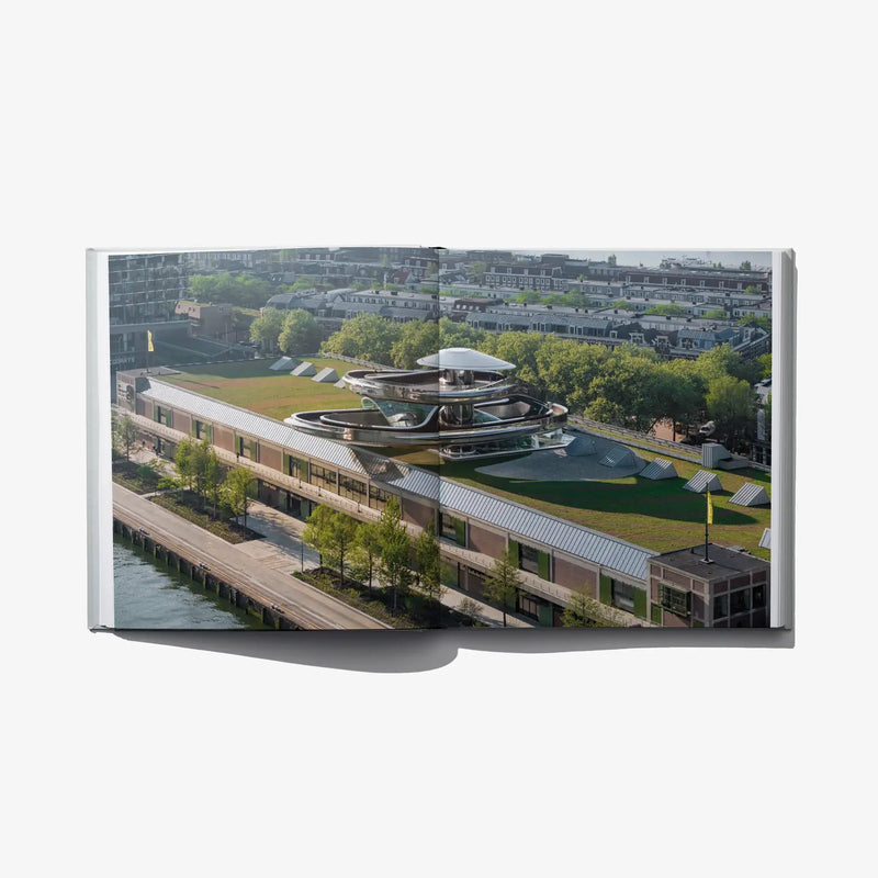 Open architecture book with an aerial view of a modern riverside building complex.
