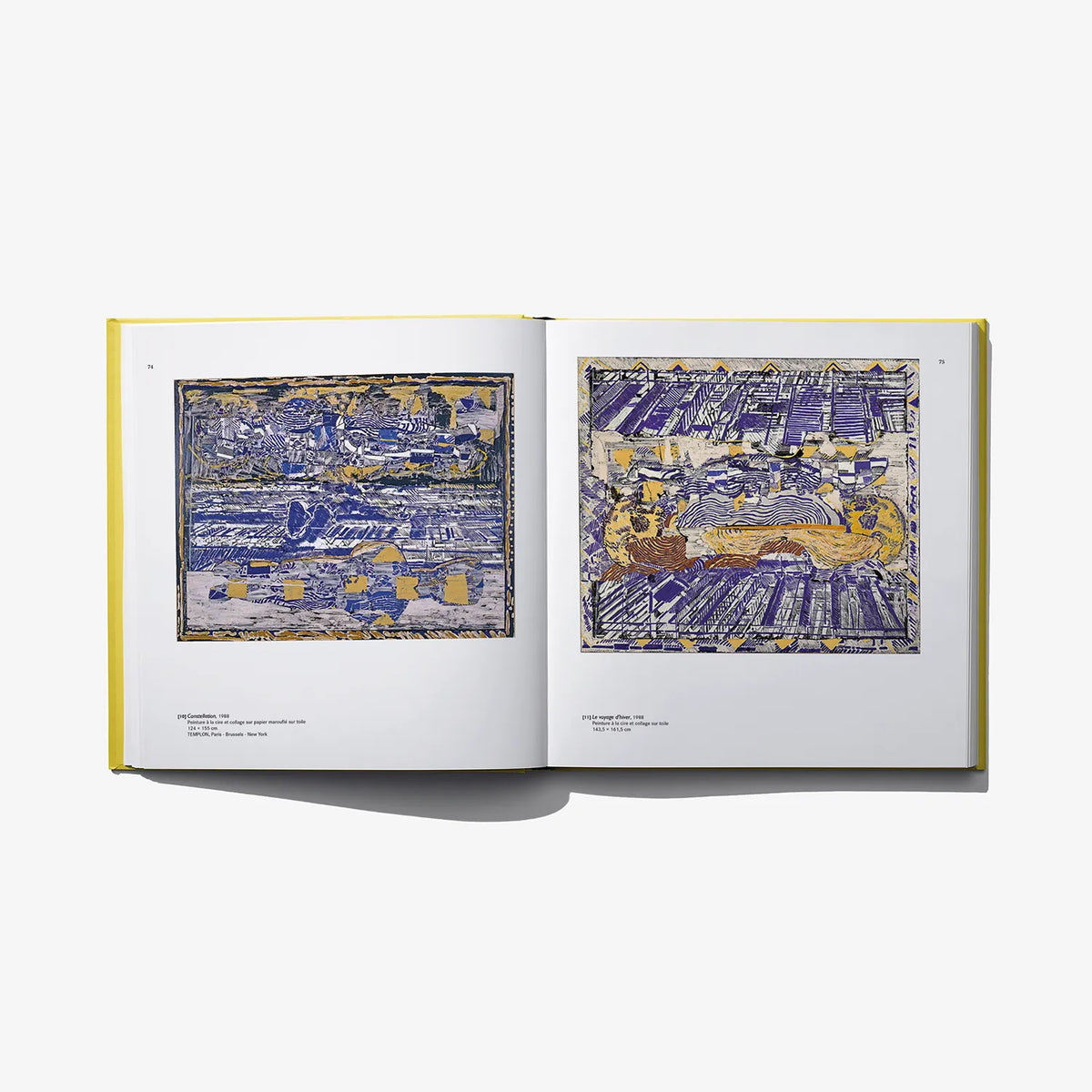 Open art book with blue and yellow abstract cityscape prints on two pages