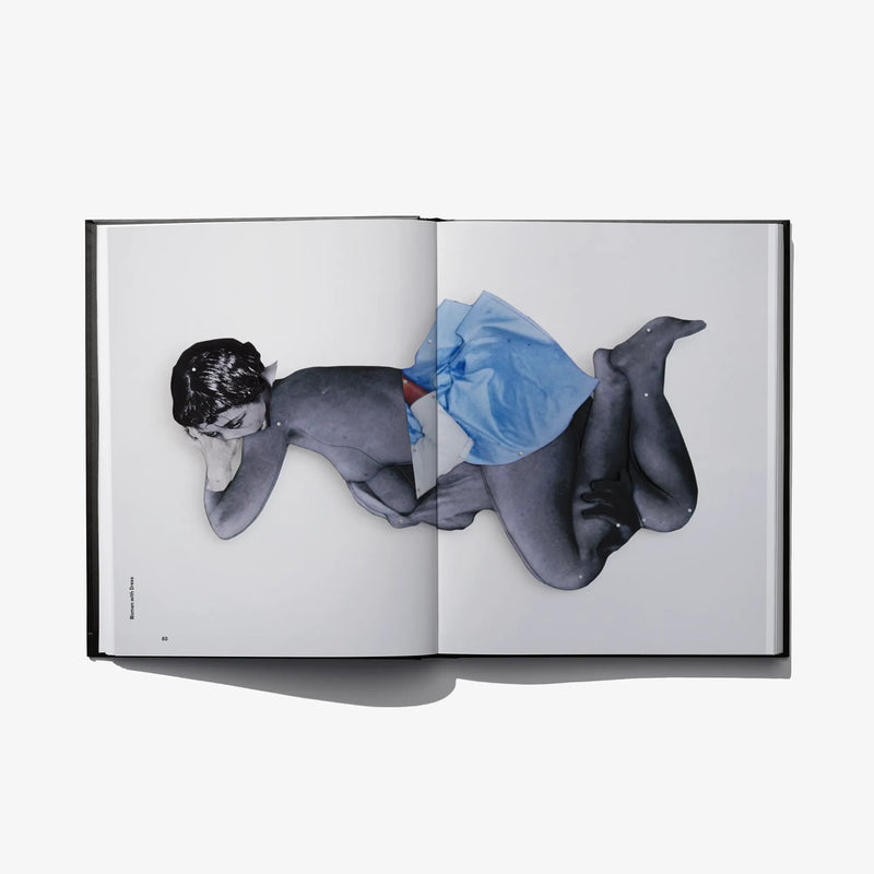 Open photo book spread with nude figures and blue cloth covering center