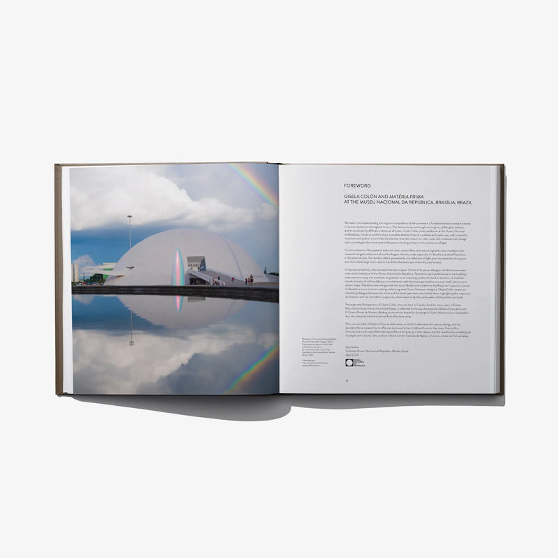 Open hardcover art book with architectural photo across left page and text on right