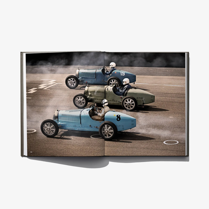 Photo book spread with two vintage race cars lined up on a track