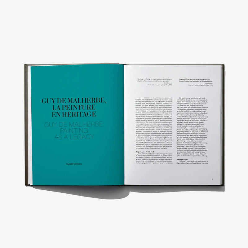 Open art book showing teal title page on the left and a dense text page on the right.