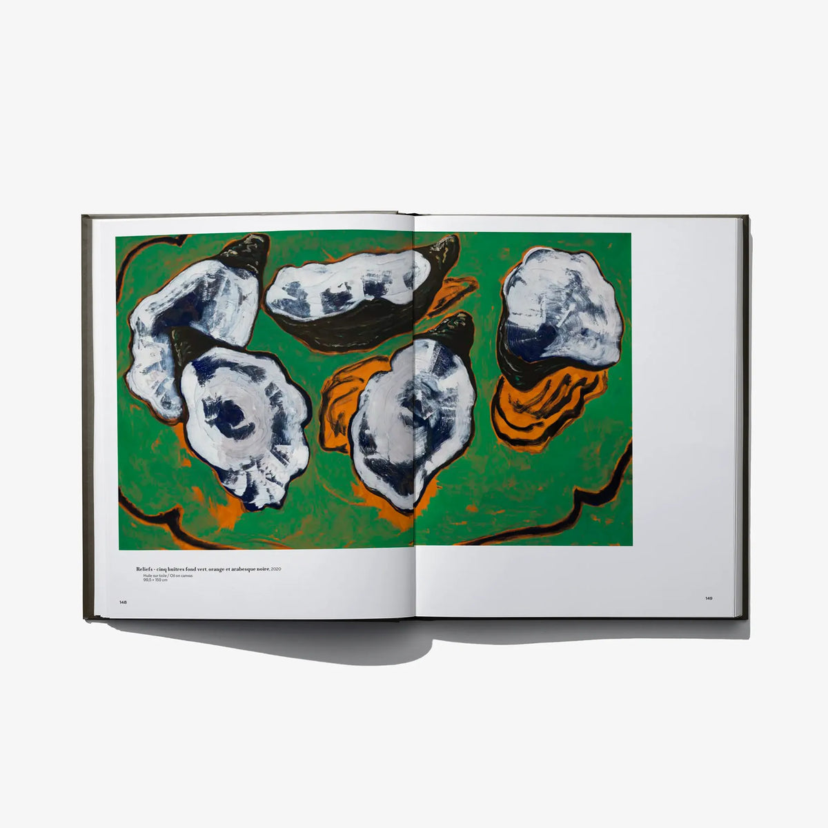 Open art book with an illustration of abstract face-like shapes on a green background.