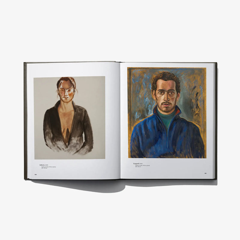 Open art book with two portraits: a dark figure sketch and a blue-toned man portrait.