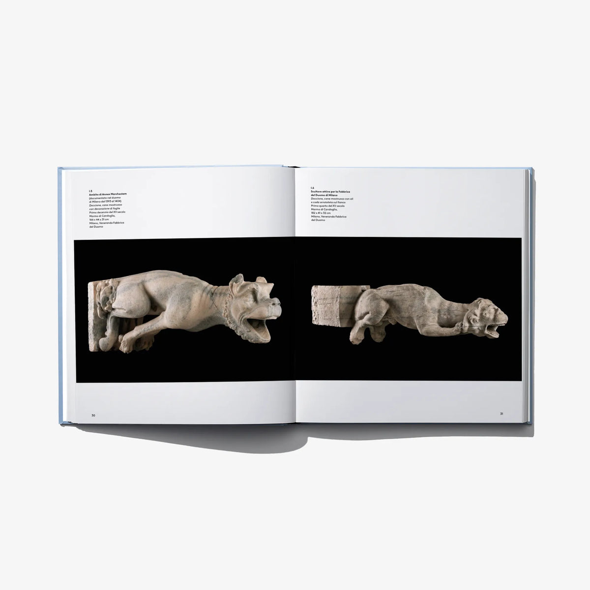 Open art book spread showing two sculpted animal figures on dark panels