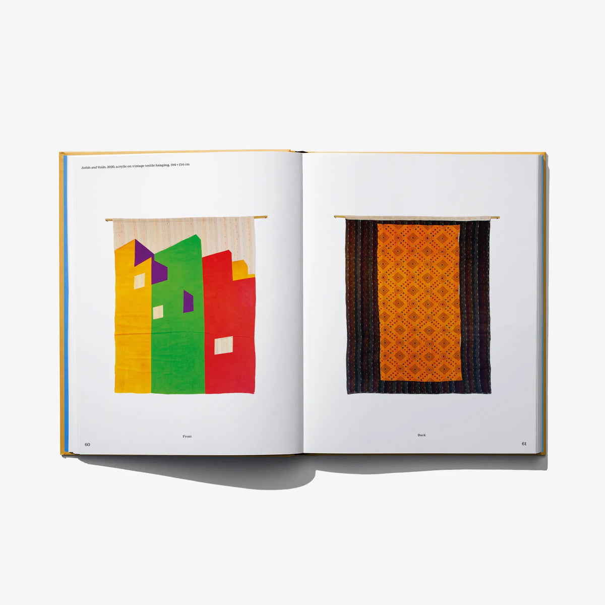 Open art book spread with two framed abstract artworks in orange and green
