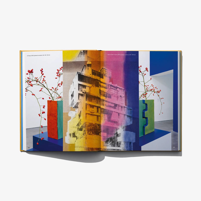 Open art book spread with colorful cityscape collage and red flowering branches