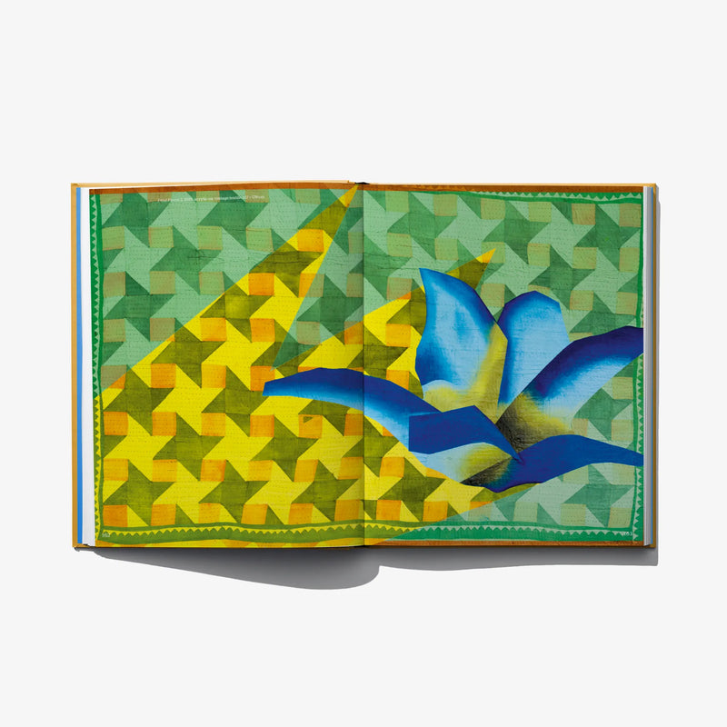 Open art book spread with large blue birds-like abstract shapes on green patterns