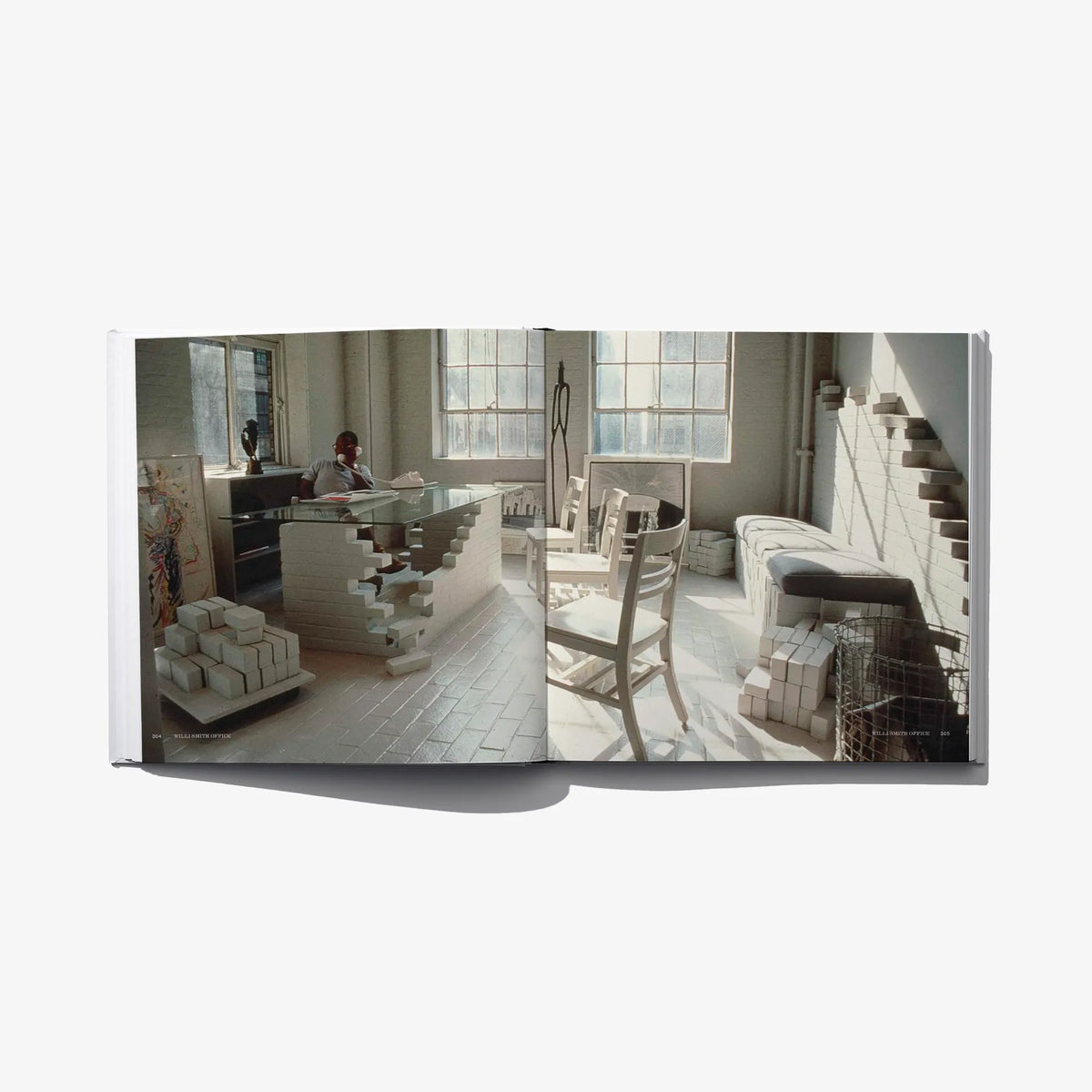 Open book page with a photo of an office/model room and stacked furniture models