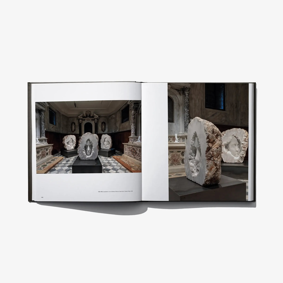 Open art book with museum room photos and stone sculptures on pedestals.