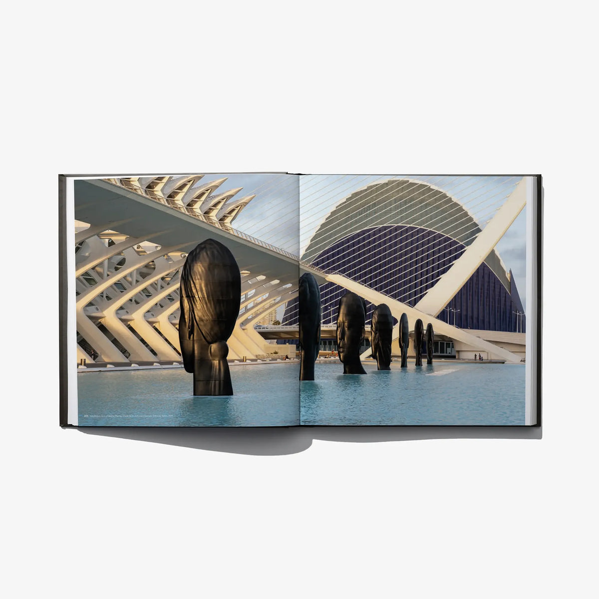 Open art book featuring a modern building, water, and dark bronze sculpture figures.