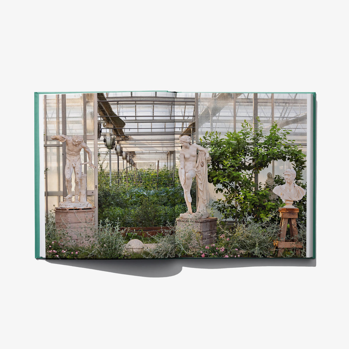 Open landscape design book showing greenhouse statues and plants across both pages