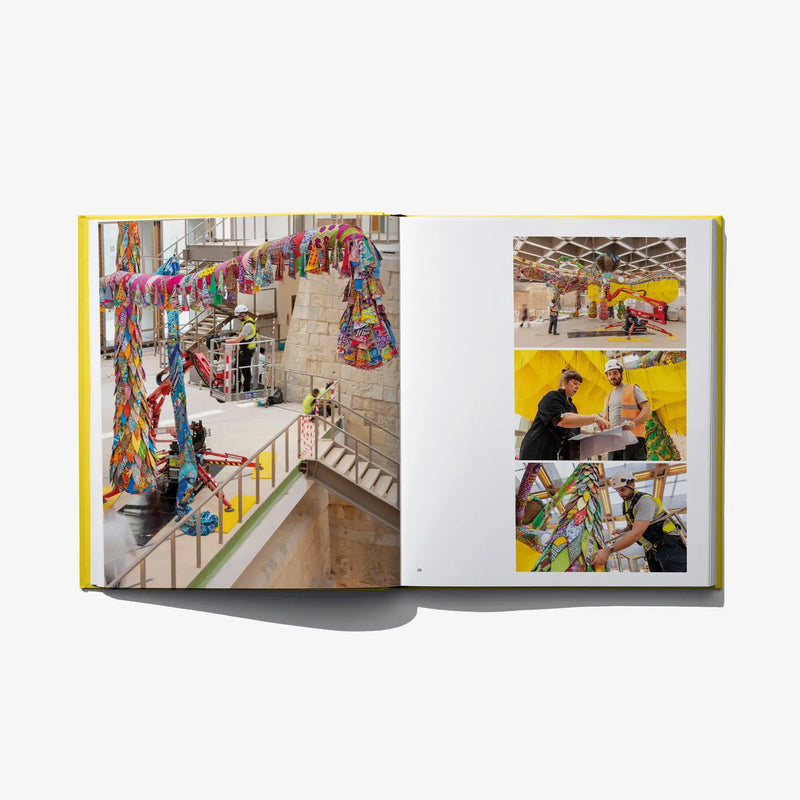 Open art book spread with photos of bright fabric installations and people.