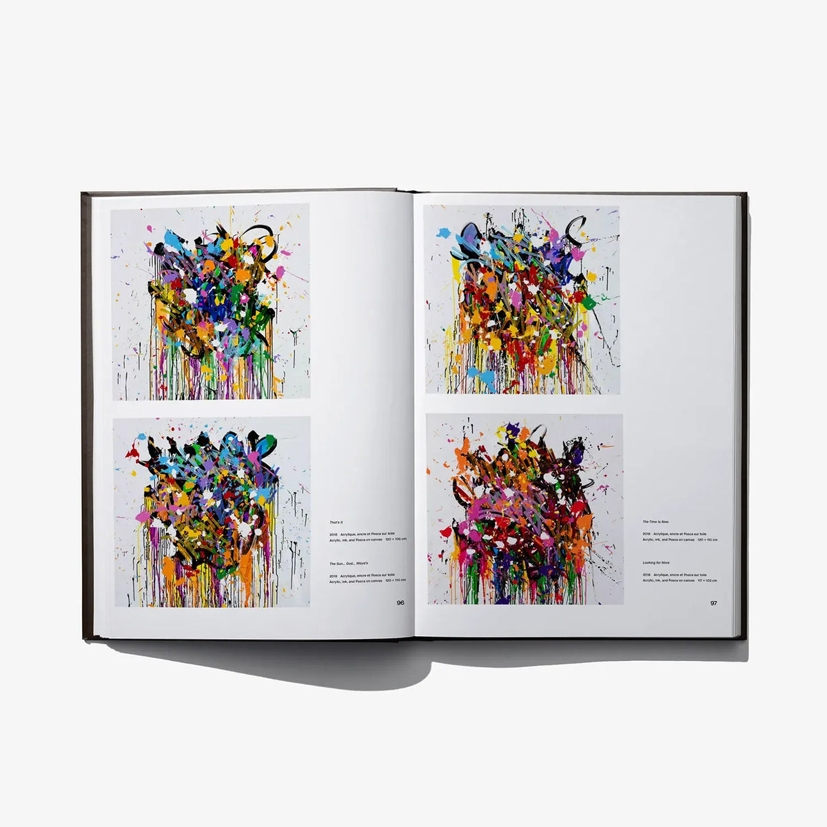 Open art book spread with four small colorful abstract artworks on white pages
