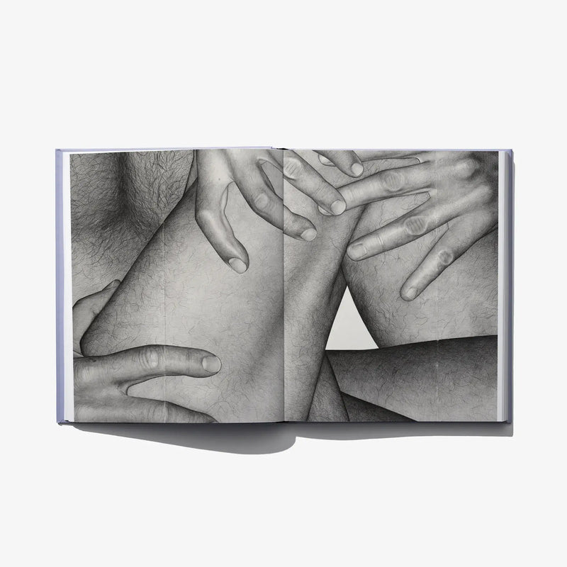 Open art book spread showing black-and-white torso and interlaced hands