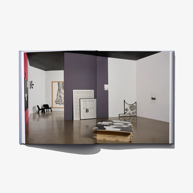 Open art book spread showing a gallery interior with framed artwork