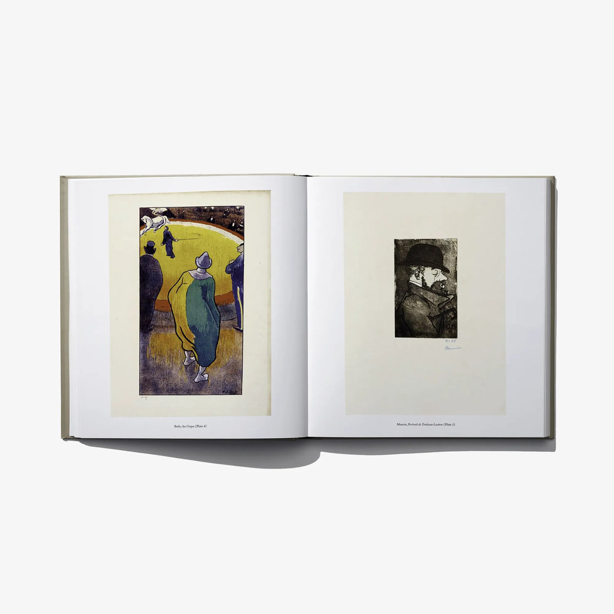 Open hardcover book showing two framed graphic prints on cream pages