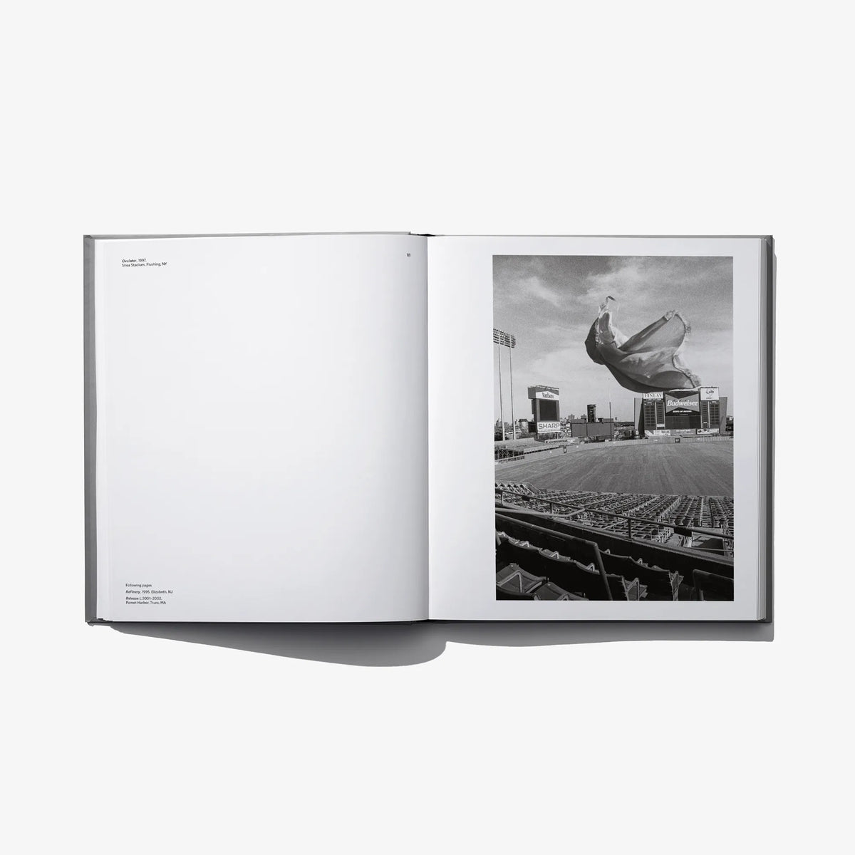 Open photo book spread with blank left page and grayscale photo of cloth in the air