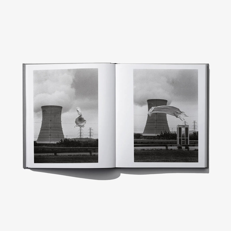 Open photo book spread with two grayscale photos of cooling towers and flying cloth