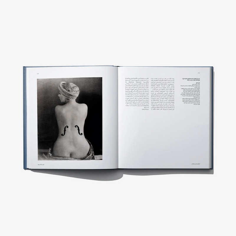 Open art book spread with black-and-white statue photo and Arabic text on white pages