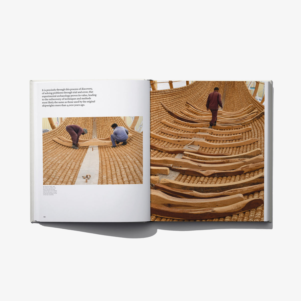 Open book spread showing wooden boat hull framework with curved ribs and workers