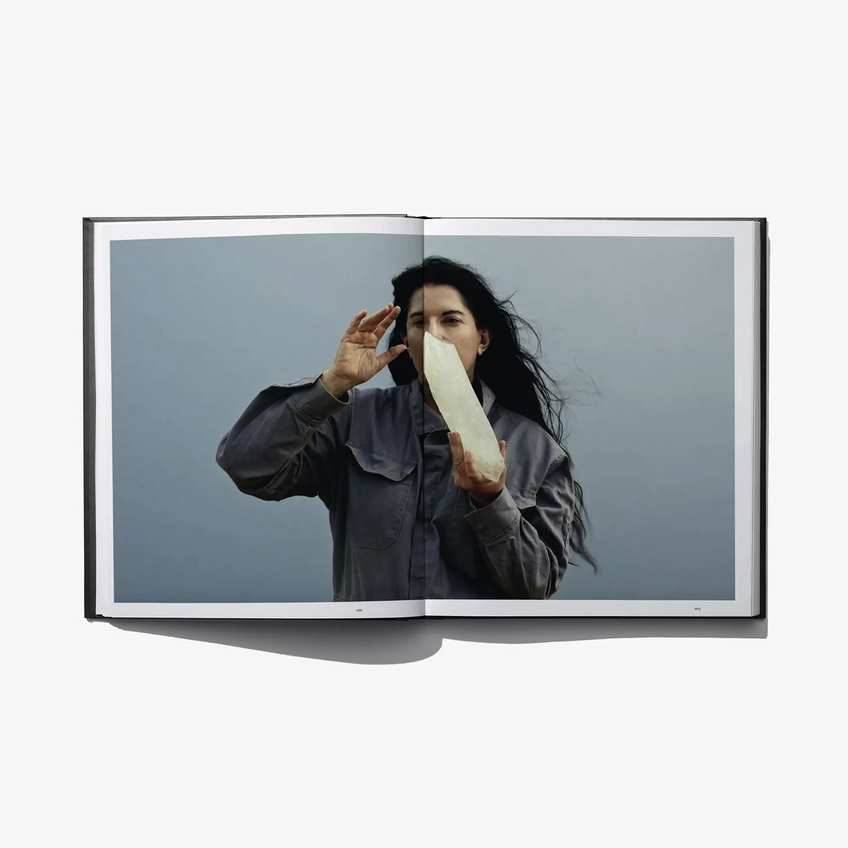 Open art book spread with person posing with hands to face